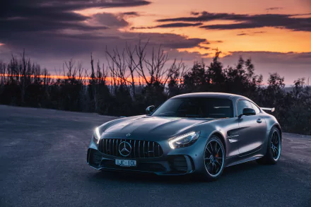 Silver Mercedes-AMG GT supercar parked on an open road at sunset, captured in high definition as a sleek, powerful vehicle in a serene, natural setting.