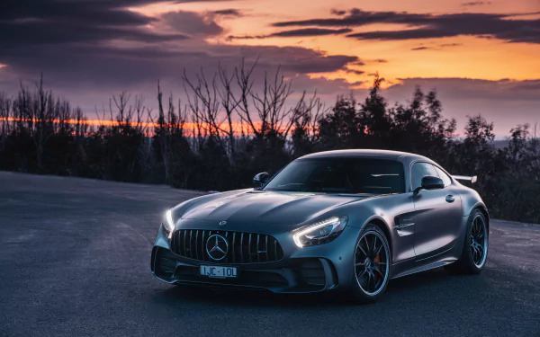 Silver Mercedes-AMG GT supercar parked on an open road at sunset, captured in high definition as a sleek, powerful vehicle in a serene, natural setting.