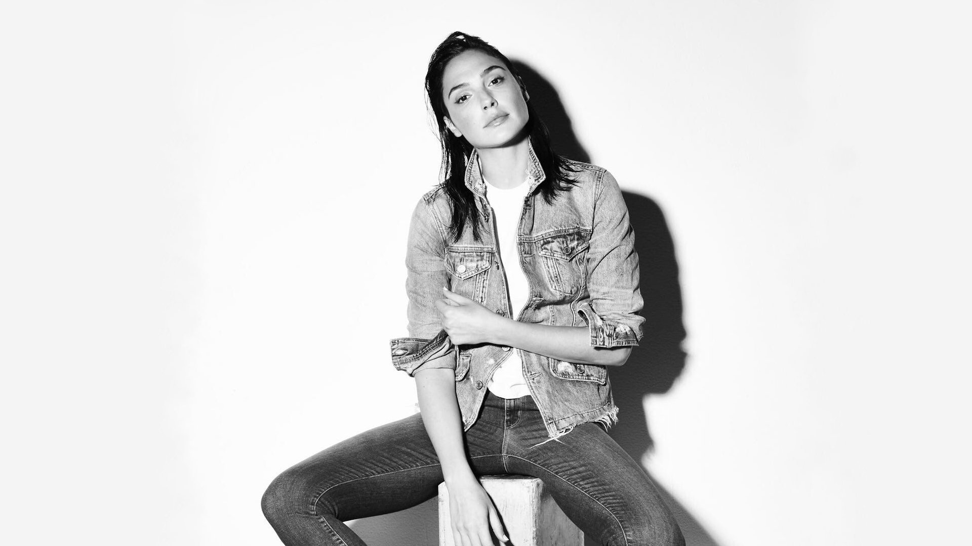 Black and white HD desktop wallpaper featuring actress Gal Gadot in a casual pose, showcasing a monochrome celebrity portrait with a stylish, modern vibe.