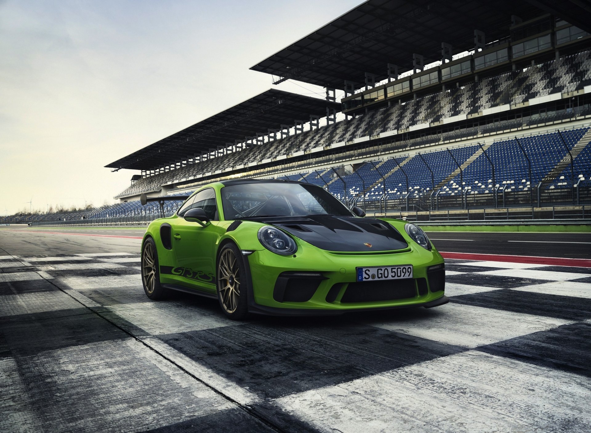 Green Porsche 911 GT3 race car parked on a racetrack under a cloudy sky, captured in HD for a striking PC desktop wallpaper.