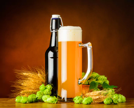 A still life 4K Ultra HD wallpaper featuring a frothy glass of beer, a dark bottle, fresh hops, and barley on a warm brown background.