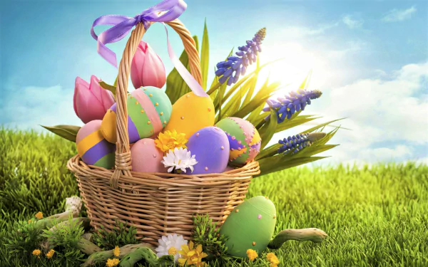 A colorful Easter basket adorned with a ribbon, filled with decorated Easter eggs and spring flowers, set on green grass under a bright sky—HD desktop wallpaper.