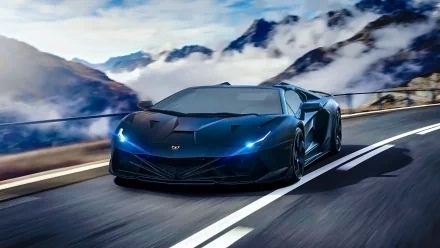 A high-definition wallpaper and background image of a sleek black Lamborghini Aventador supercar speeding on a winding mountain road with a cloudy sky and scenic mountain landscape in the background.