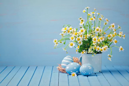 A 4K Ultra HD desktop wallpaper featuring white camomile flowers in a white pot alongside pastel Easter eggs on a light blue wooden surface.