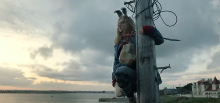 HD desktop wallpaper of Madison Wolfe from I Kill Giants, sitting on a pole with a scenic backdrop.