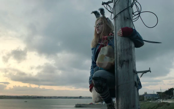 HD desktop wallpaper of Madison Wolfe from I Kill Giants, sitting on a pole with a scenic backdrop.
