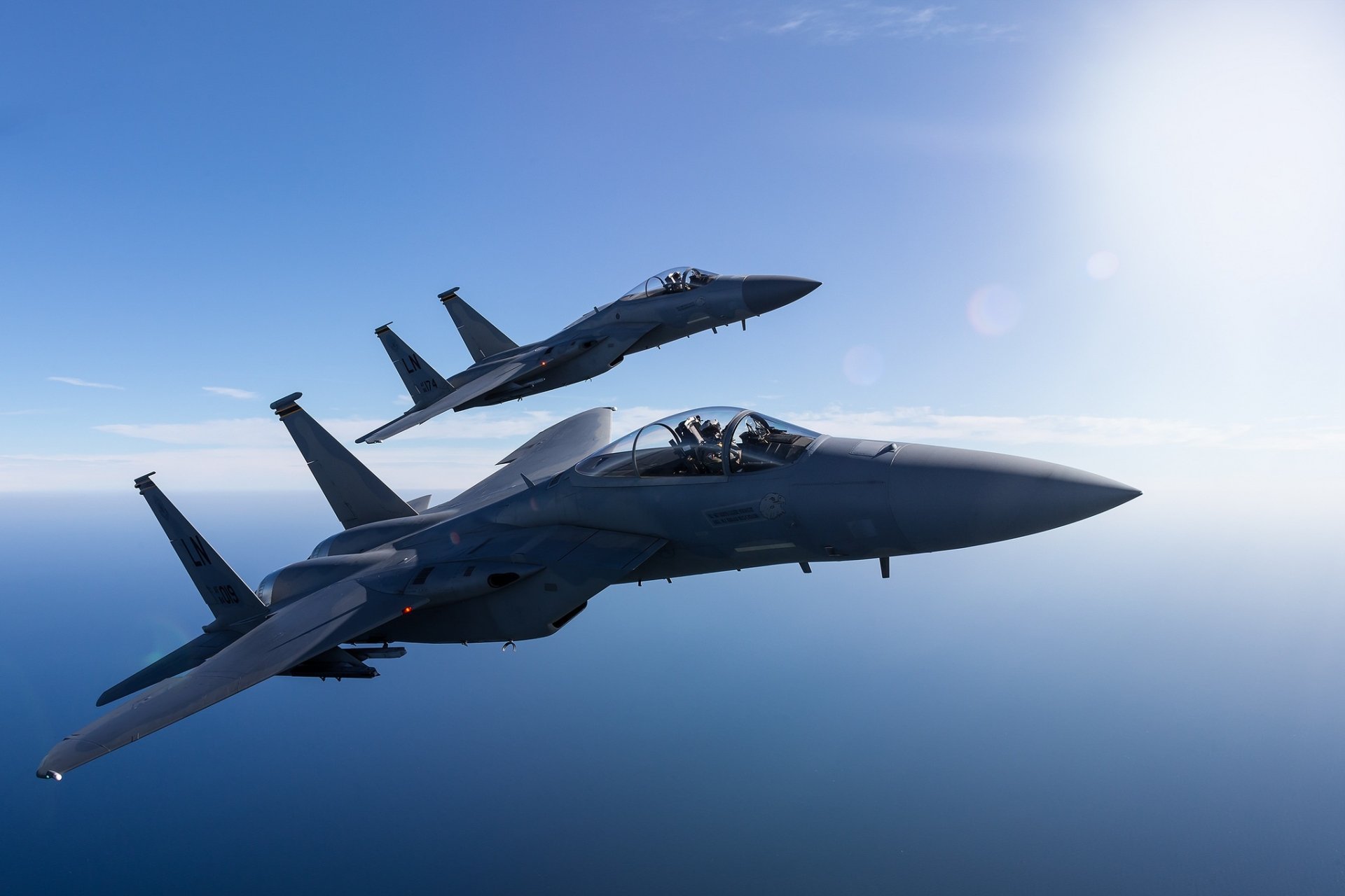 Two McDonnell Douglas F-15 Eagle jet fighter warplanes fly side by side over a clear blue sky in this HD military aircraft wallpaper.