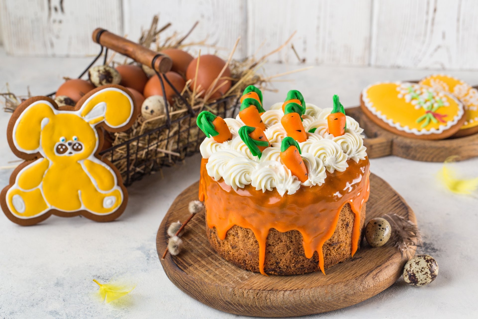 A vibrant 4K Ultra HD still life desktop wallpaper featuring a carrot cake topped with cream and small carrot decorations, alongside an egg and bunny-shaped pastry on a rustic table.
