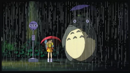 HD wallpaper featuring Totoro, Mei Kusakabe, and Satsuki Kusakabe from My Neighbor Totoro standing in the rain with umbrellas at a bus stop.