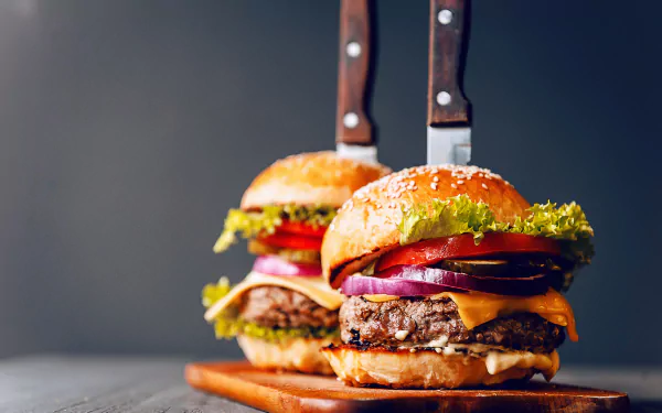 4K Ultra HD PC desktop wallpaper/background: close-up of two juicy cheeseburgers with lettuce, tomato, red onion and knives through the buns — food, burger.