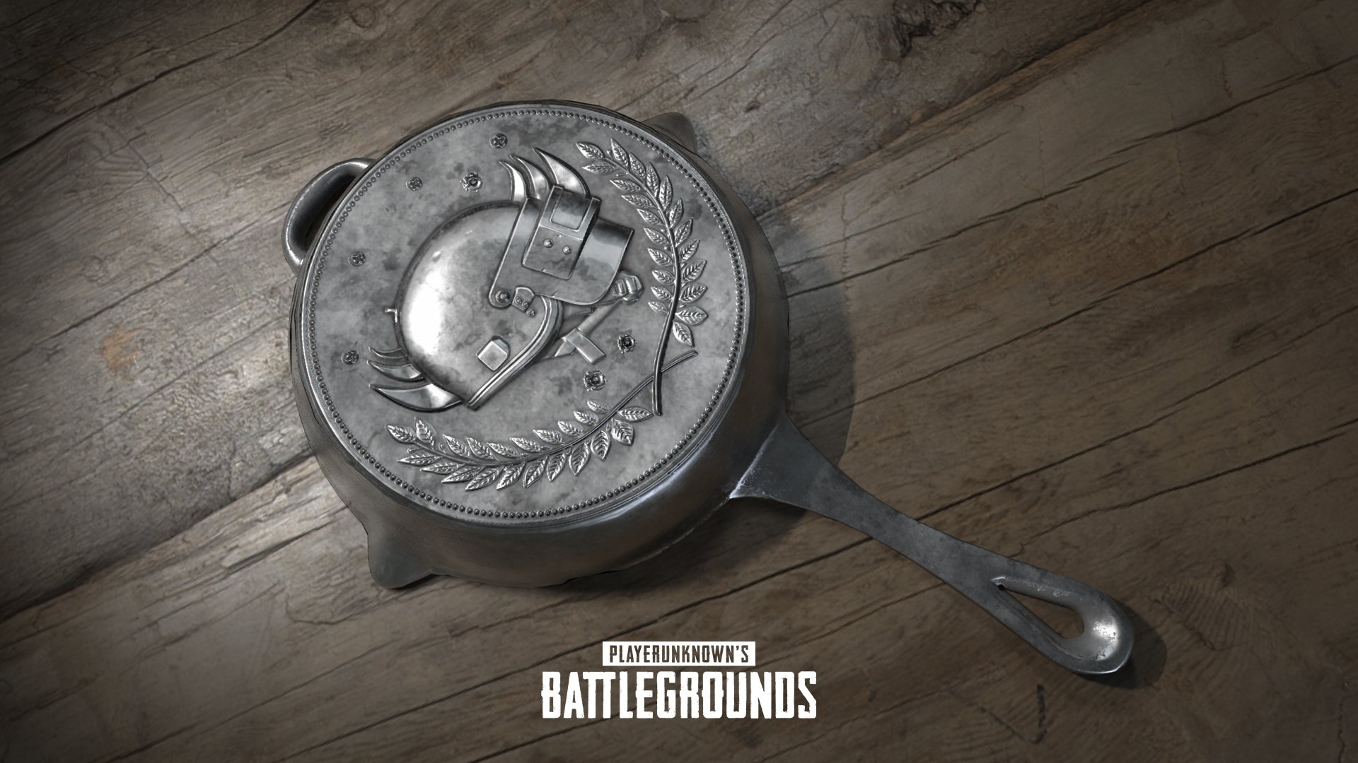 HD desktop wallpaper featuring a detailed metal pan emblazoned with a helmeted logo from Playerunknown's Battlegrounds, set against a wooden background.