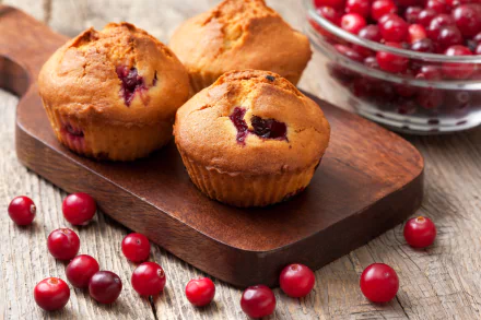 Close-up of three currant muffins on a wooden board surrounded by fresh red currants and a glass bowl, captured in HD for a vibrant desktop wallpaper background.