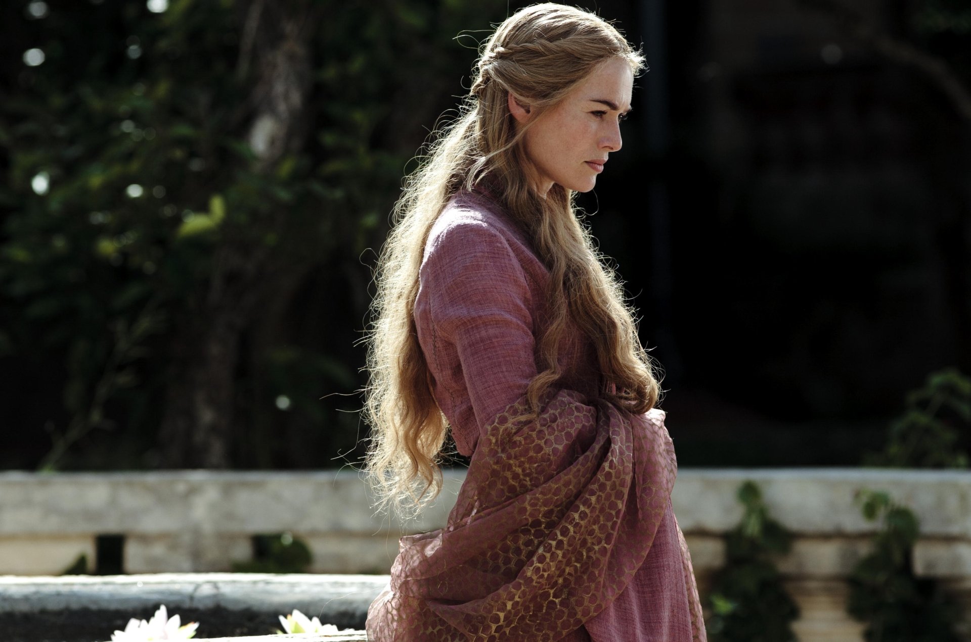 Cersei Lannister in a rich gown, side profile on a stone balcony amid garden foliage — Game of Thrones TV show 2K Quad HD PC desktop wallpaper.