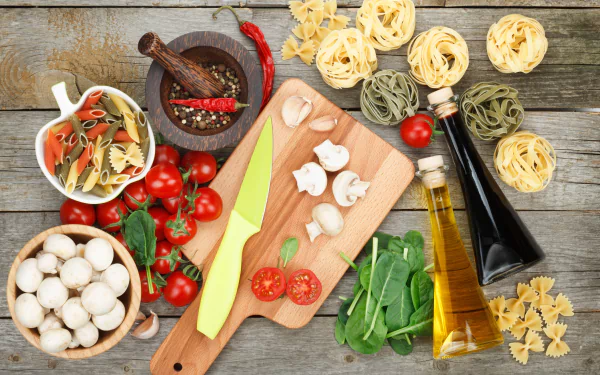 4K Ultra HD PC desktop wallpaper food still life: pasta nests, mushrooms, cherry tomatoes, herbs, olive oil and spices arranged on a rustic wooden board.