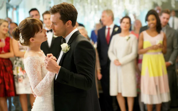 HD wallpaper of a wedding scene from Fifty Shades Freed with a couple dancing and guests in the background.