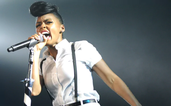 HD wallpaper of a dynamic performance, featuring a singer with a unique hairstyle, singing passionately into a microphone on stage.