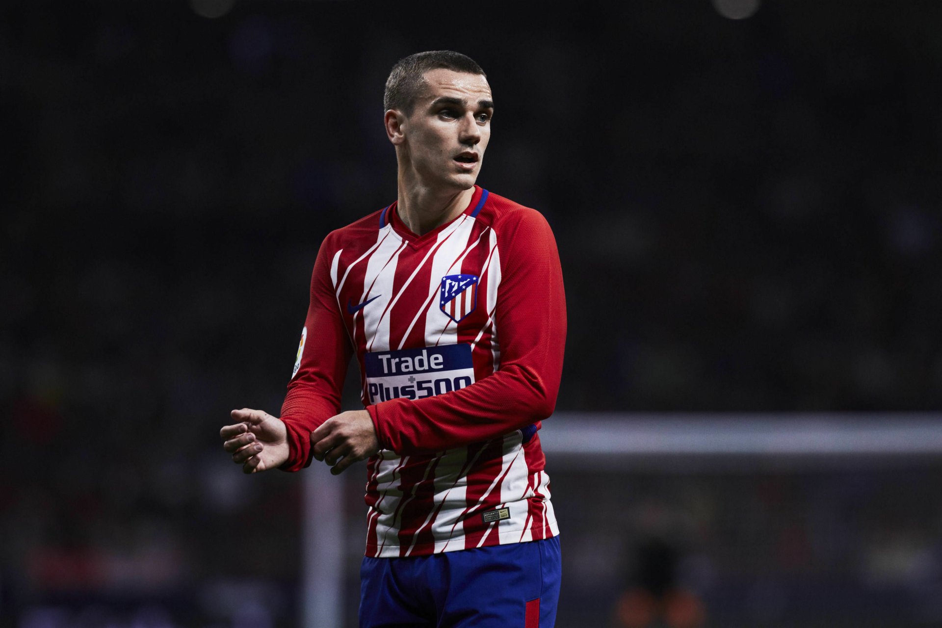 French soccer forward in Atlético Madrid red-and-white kit on the pitch, sports action shot rendered as a 2K Quad HD PC desktop wallpaper.