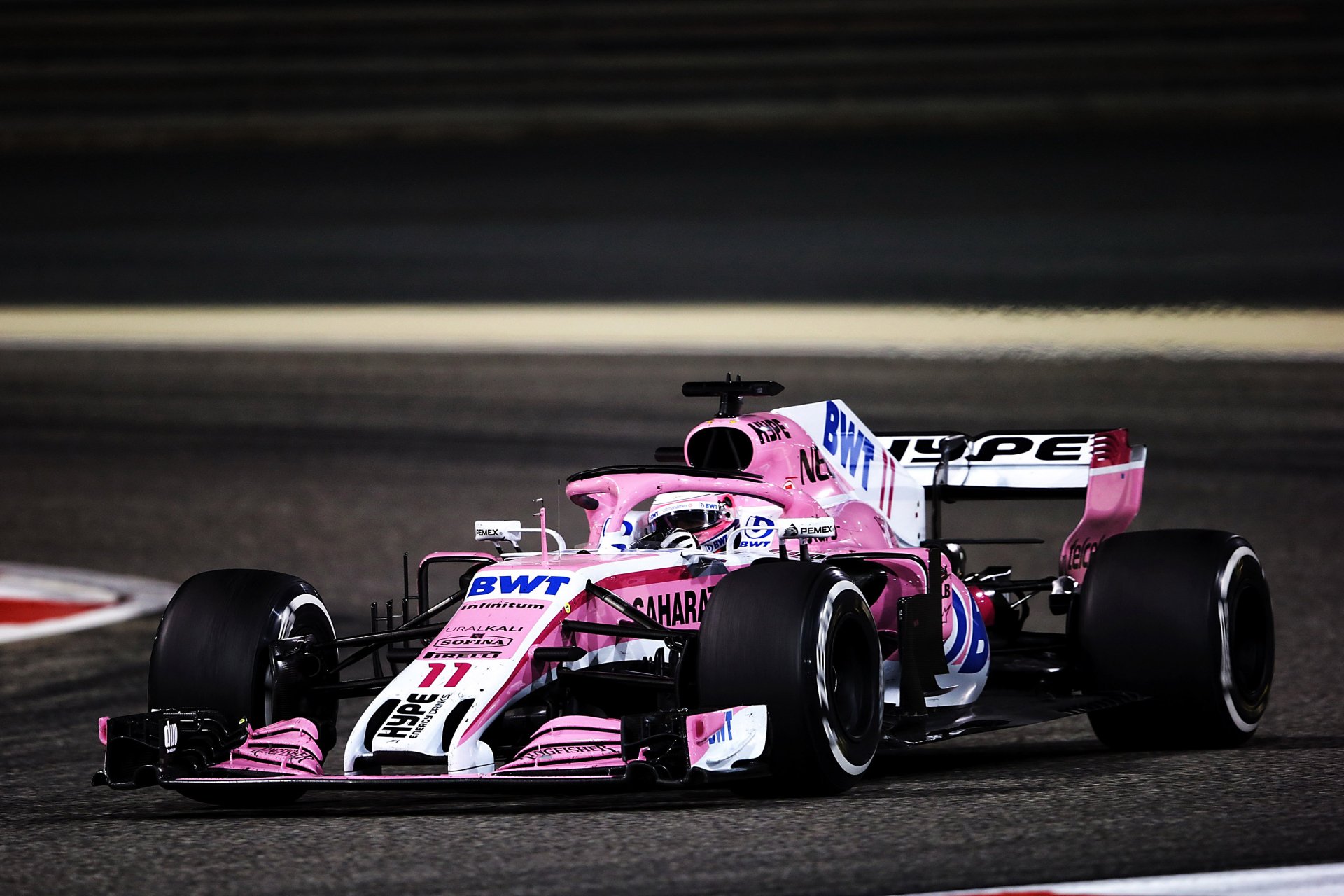 F1 sports 2K Quad HD PC desktop wallpaper/background: pink Formula 1 car racing on track with motion blur and dramatic lighting