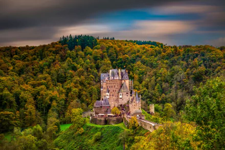 Eltz Castle, a man-made architectural marvel, nestled in a dense forest under a vibrant sky, captured in stunning HD for a PC desktop wallpaper.