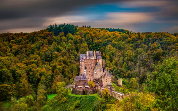 Eltz Castle, a man-made architectural marvel, nestled in a dense forest under a vibrant sky, captured in stunning HD for a PC desktop wallpaper.