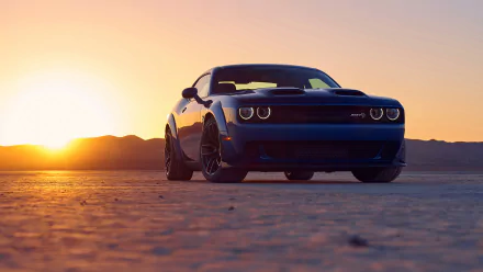 A Dodge Challenger SRT Hellcat parked on a desert plain at sunset, captured in an HD PC desktop wallpaper with warm golden light and a clear sky.