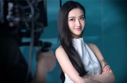 HD desktop wallpaper featuring a poised individual, tagged as Jing Tian, against a teal backdrop with camera equipment partially visible.
