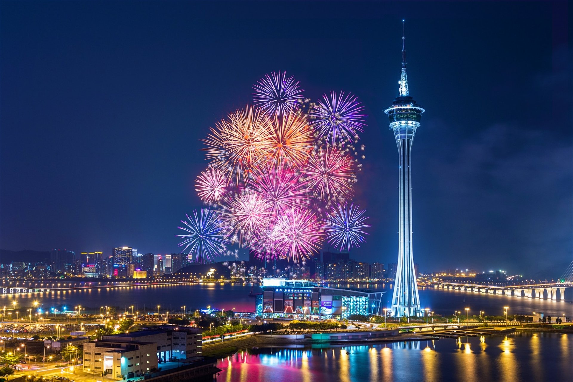 HD cityscape wallpaper of a Chinese skyline at night, illuminated by colorful fireworks and vibrant lights around a tall tower.