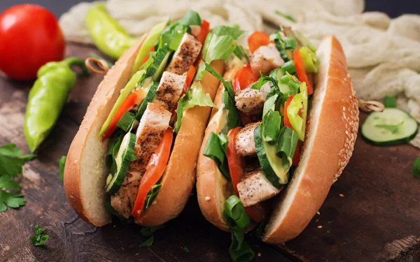 Close-up of two grilled chicken hot dogs with fresh vegetables in buns, styled as a 4K Ultra HD still life food desktop wallpaper.