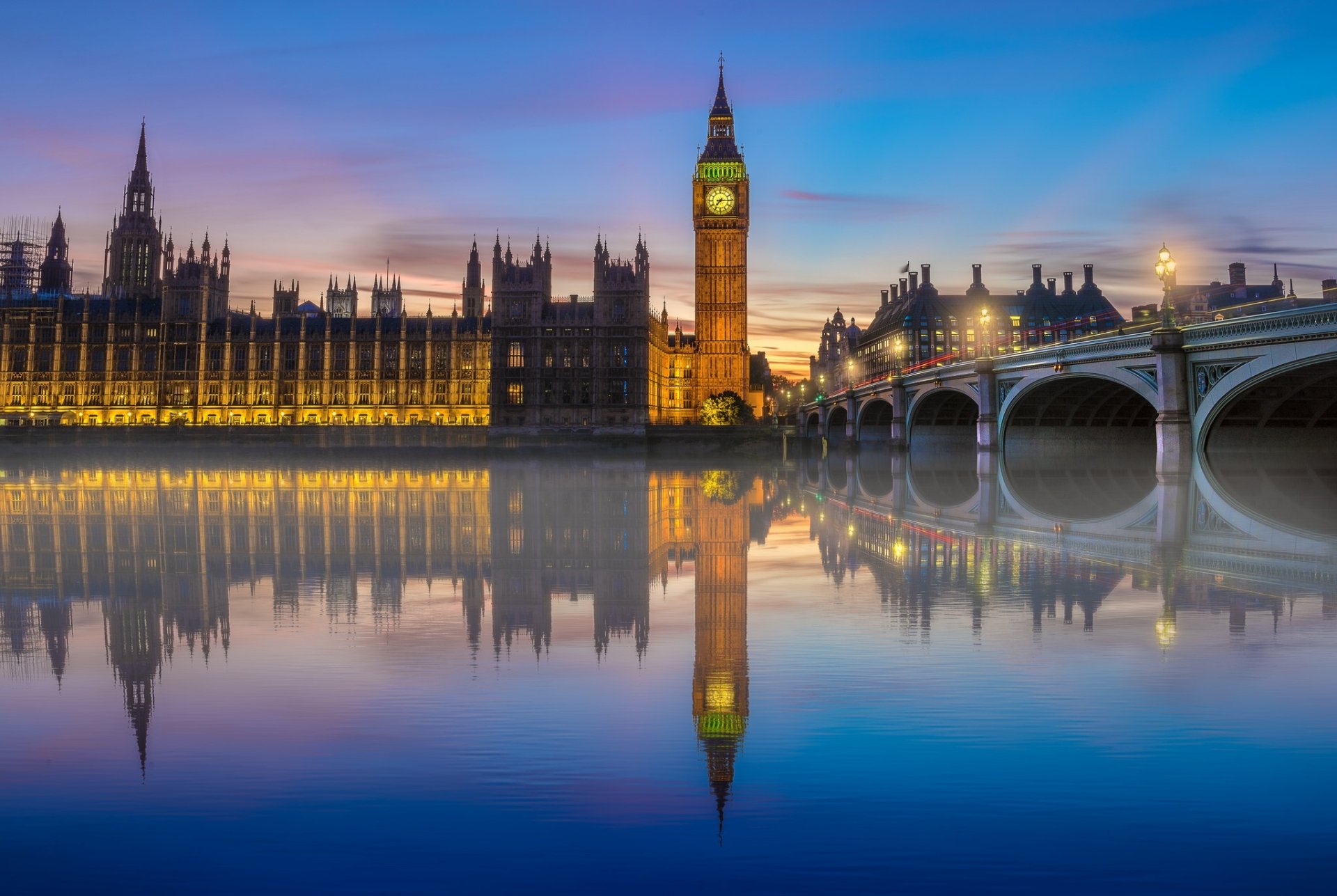 HD desktop wallpaper of Big Ben in London reflected in the Thames River at dusk. The image showcases the iconic building and bridge with a serene water reflection, capturing the essence of the United Kingdom's capital.