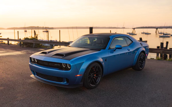 A blue Dodge Challenger SRT muscle car parked near a waterfront at sunset, showcased as an HD desktop wallpaper and background.