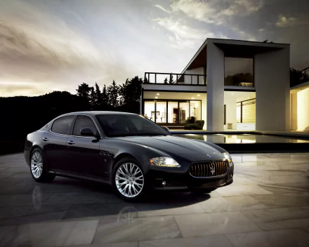 A sleek black Maserati Quattroporte parked at night in front of a modern house, captured in high-definition as a PC desktop wallpaper background.