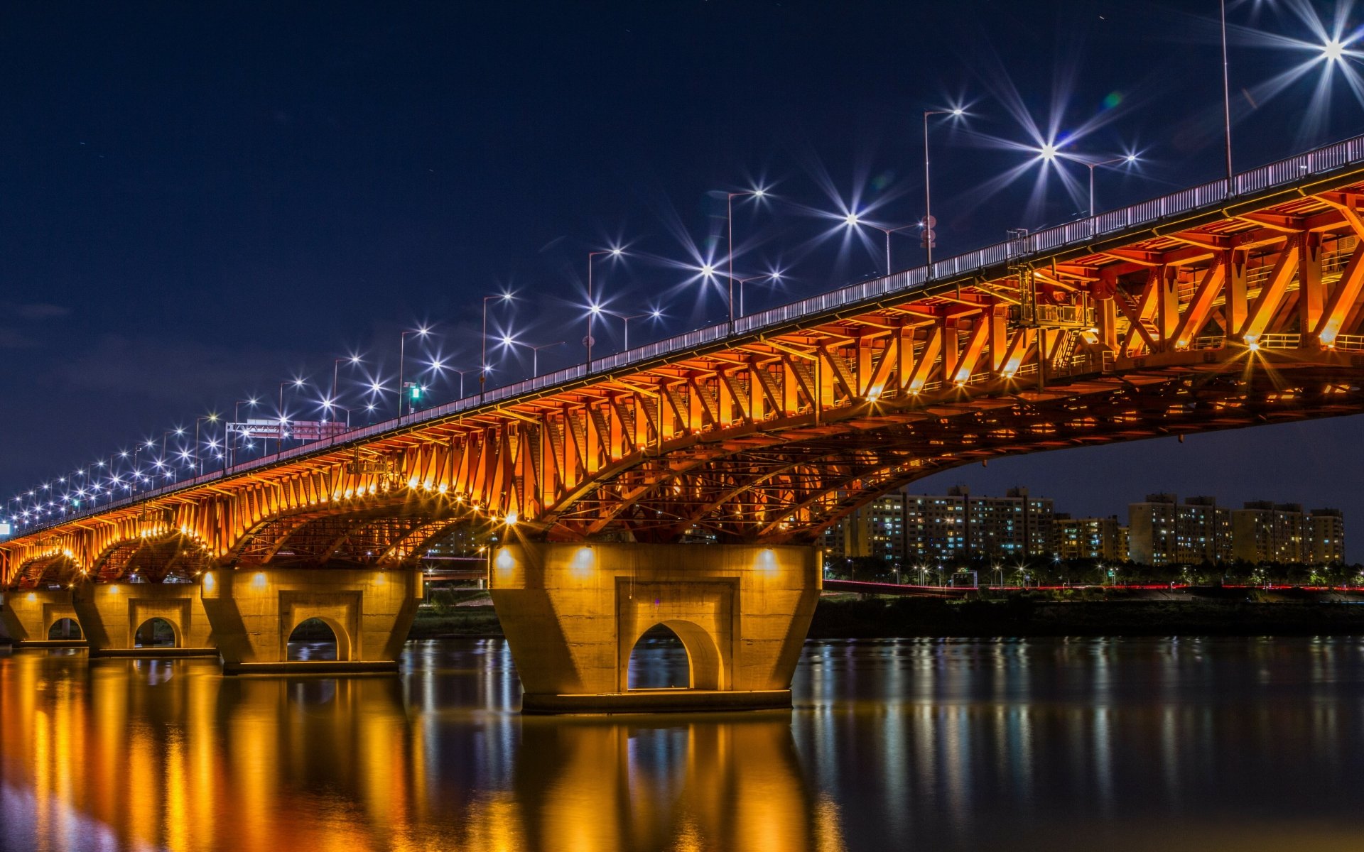 Night view of the illuminated Seongsu Bridge in Seoul, South Korea, reflecting on the calm river beneath a starry sky in this 4K Ultra HD desktop wallpaper.