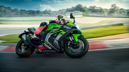HD PC desktop wallpaper of a green Kawasaki vehicle — the Kawasaki Ninja ZX-10R sportbike — leaning through a racetrack turn with a rider in red and black leathers.
