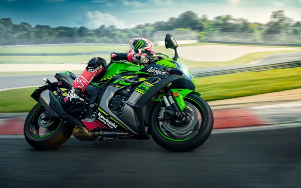 HD PC desktop wallpaper of a green Kawasaki vehicle — the Kawasaki Ninja ZX-10R sportbike — leaning through a racetrack turn with a rider in red and black leathers.
