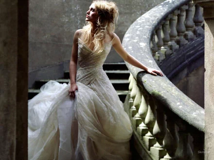 Keira Knightley stands elegantly on a staircase, wearing a stunning gown that cascades around her, captured in a striking HD wallpaper background.