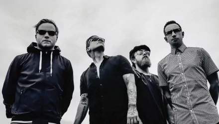 Black and white HD wallpaper featuring the rock band Shinedown, showcasing the four members in stylish attire against a cloudy background, embodying a powerful musical vibe.