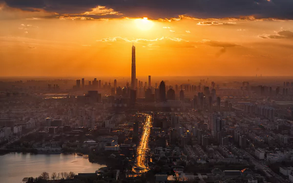 5K Ultra HD Tianjin cityscape at sunset: a man-made skyline with a towering landmark and a glowing avenue leading through the urban landscape — desktop wallpaper.