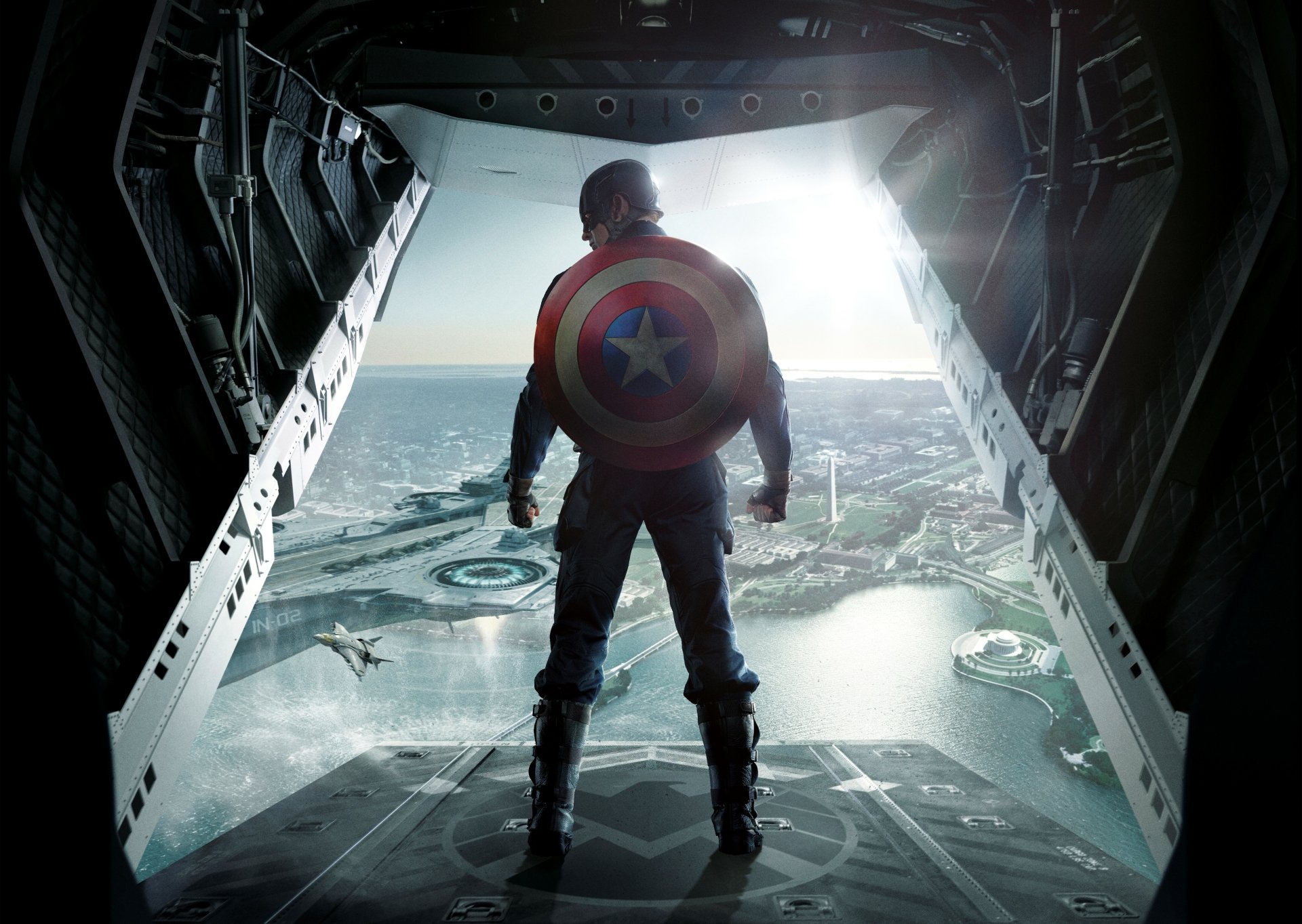 HD wallpaper of Captain America (Chris Evans) from Captain America: The Winter Soldier, standing in the open ramp of an aircraft, looking out over a cityscape with his shield on his back.
