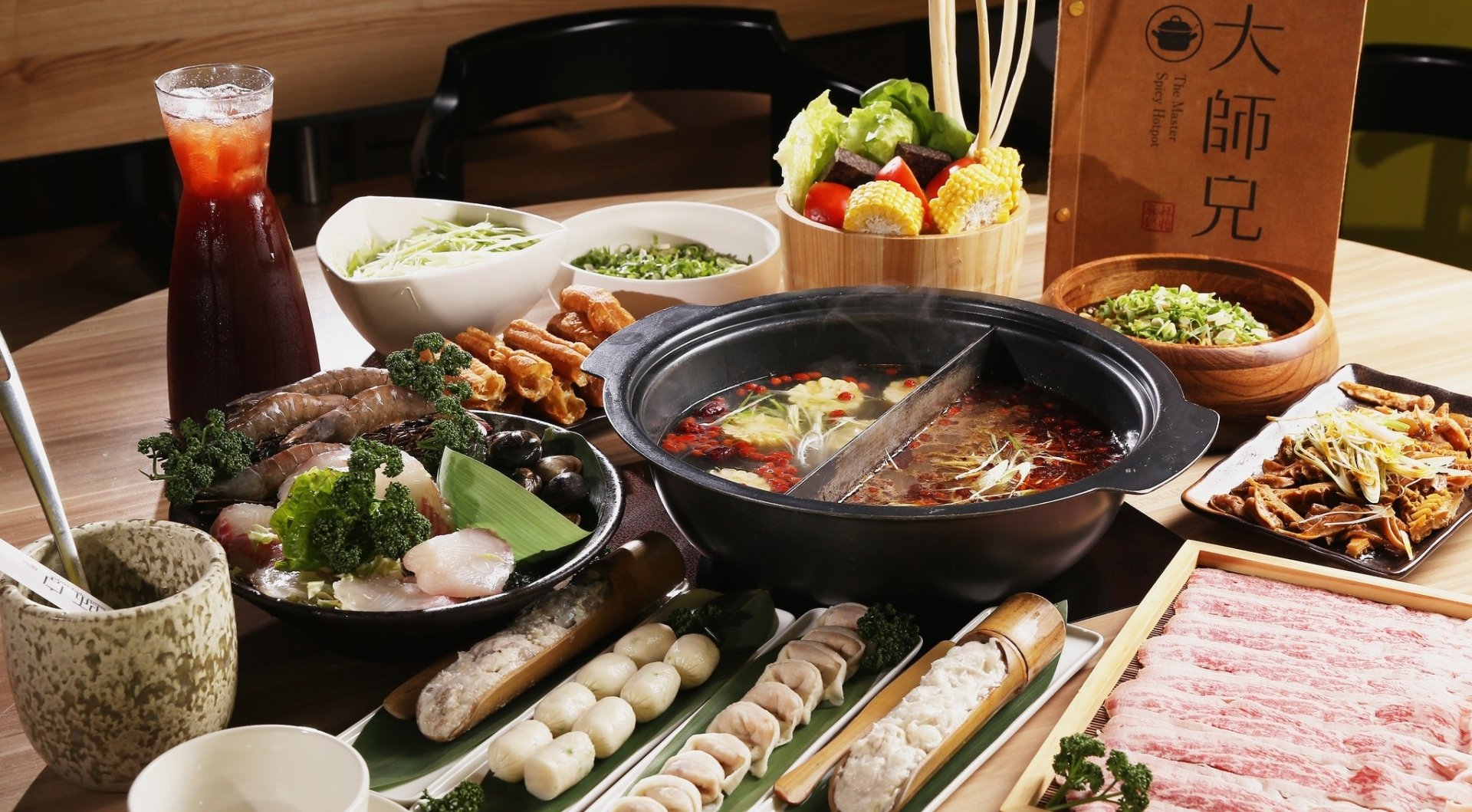 HD PC desktop wallpaper and background: meal still life featuring a hot pot with dual broth, surrounded by plates of meats, seafood, vegetables, skewers and dipping sauces on a wooden table.