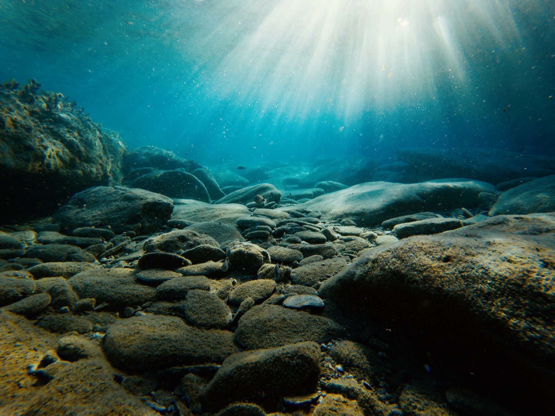 Underwater photography featuring sunbeams penetrating clear water over smooth rocks, captured in HD for a stunning PC desktop wallpaper and background.