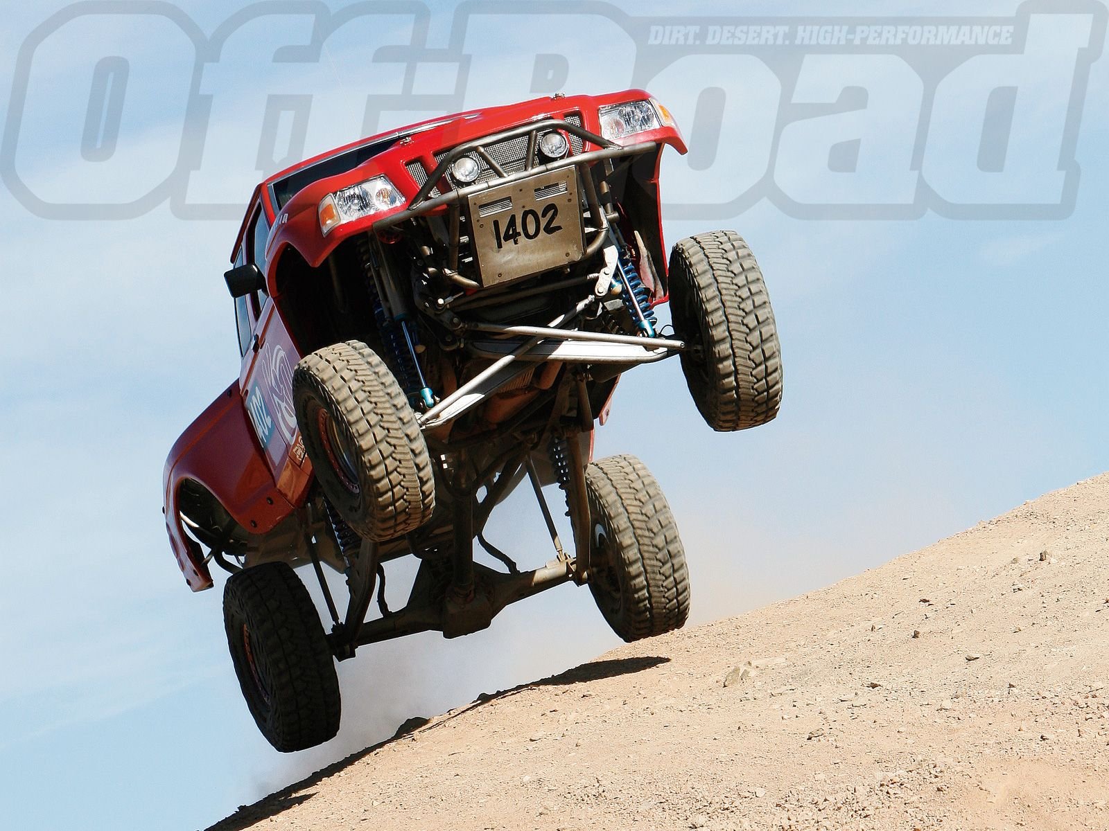 A dynamic HD image of a red Ford Ranger off-road vehicle leaping over a sandy dune, showcasing its rugged design and power in action.