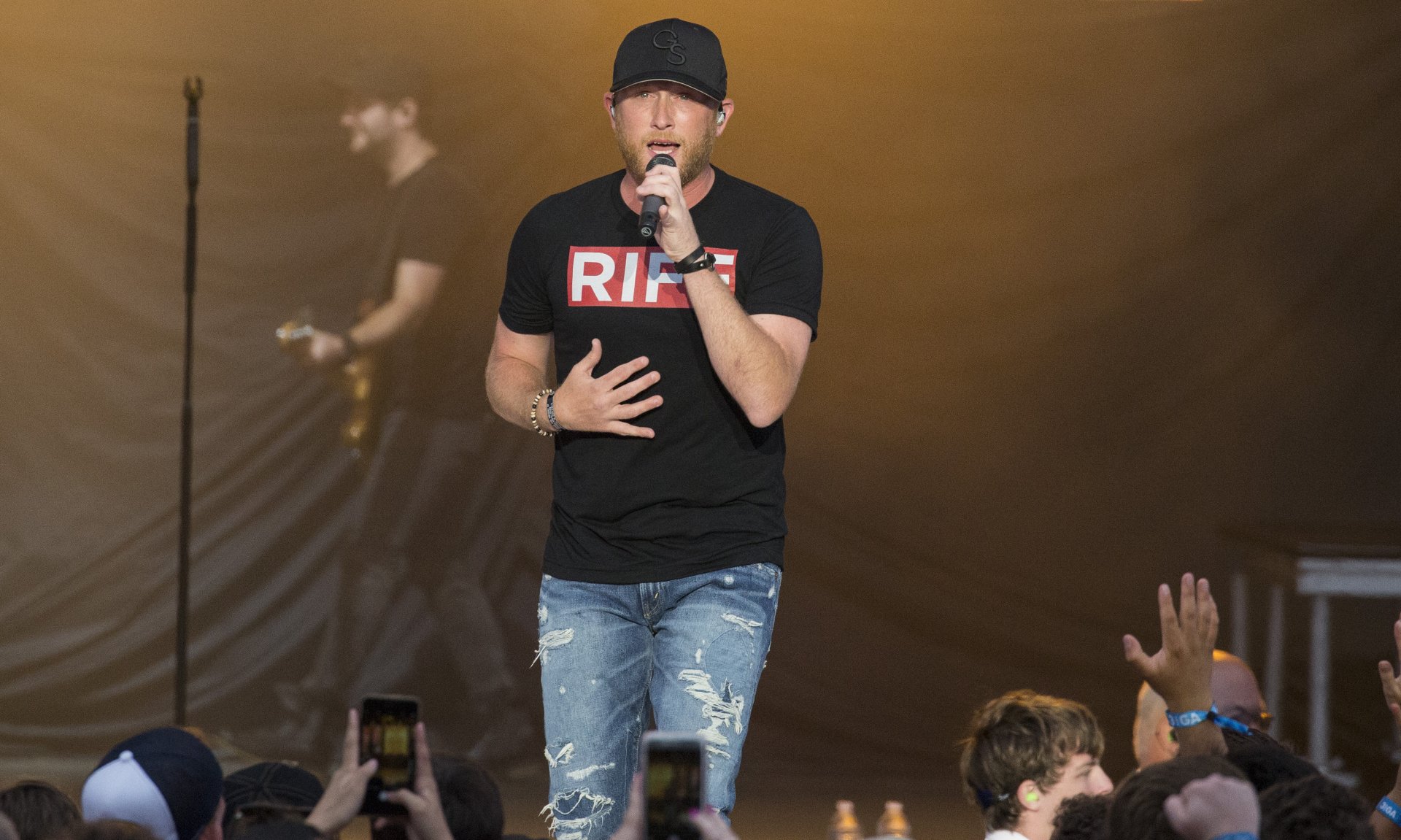 HD wallpaper of a performer on stage singing to an audience, serving as a desktop background.