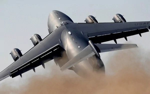 A Boeing C-17 Globemaster III takes off, kicking up a cloud of dust as its powerful engines roar. This high-definition image serves as a striking military-themed desktop wallpaper.