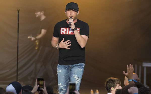 HD wallpaper of a performer on stage singing to an audience, serving as a desktop background.