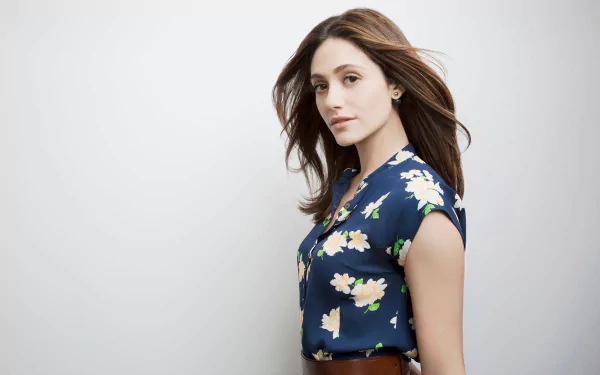 HD desktop wallpaper featuring American actress Emmy Rossum with brown eyes and brunette hair, wearing a floral top against a plain background.