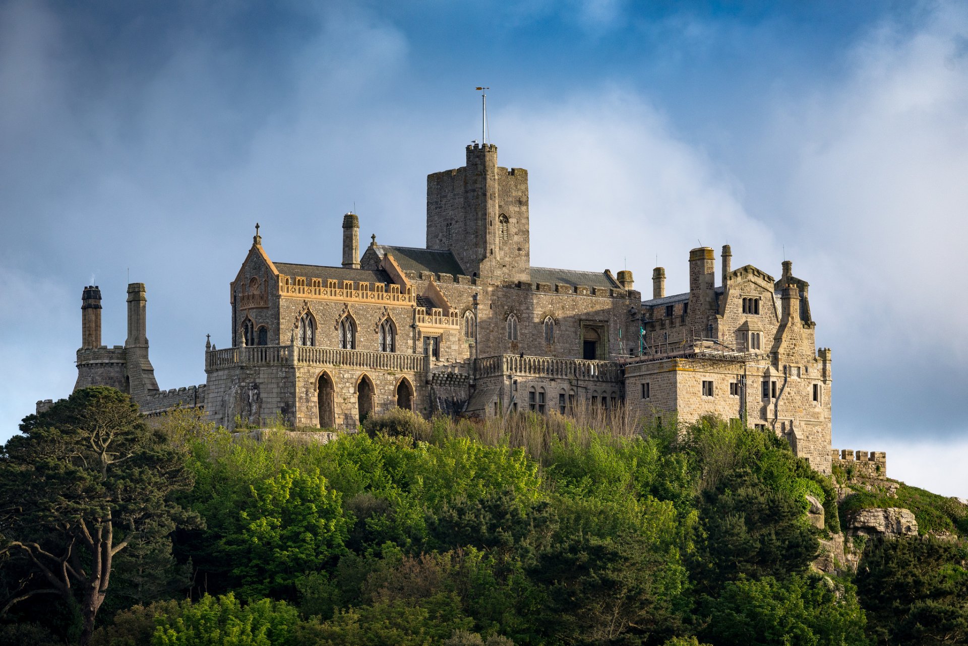 HD desktop wallpaper featuring a historic man-made castle perched atop a lush green hill under a cloudy sky.