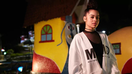 HD wallpaper featuring Ella Mai in a stylish outfit with a colorful, whimsical background.