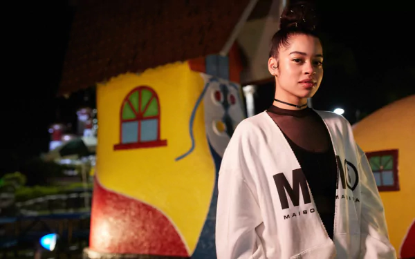 HD wallpaper featuring Ella Mai in a stylish outfit with a colorful, whimsical background.