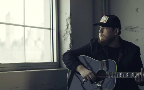 HD desktop wallpaper featuring a pensive man with a guitar by a window, evoking a reflective mood.