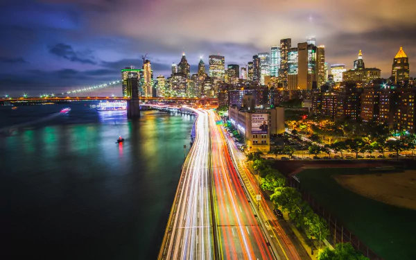 Time-lapse HD wallpaper of the Brooklyn Bridge and Manhattan skyscrapers at night in New York City, USA, showcasing vibrant city lights and urban architecture.